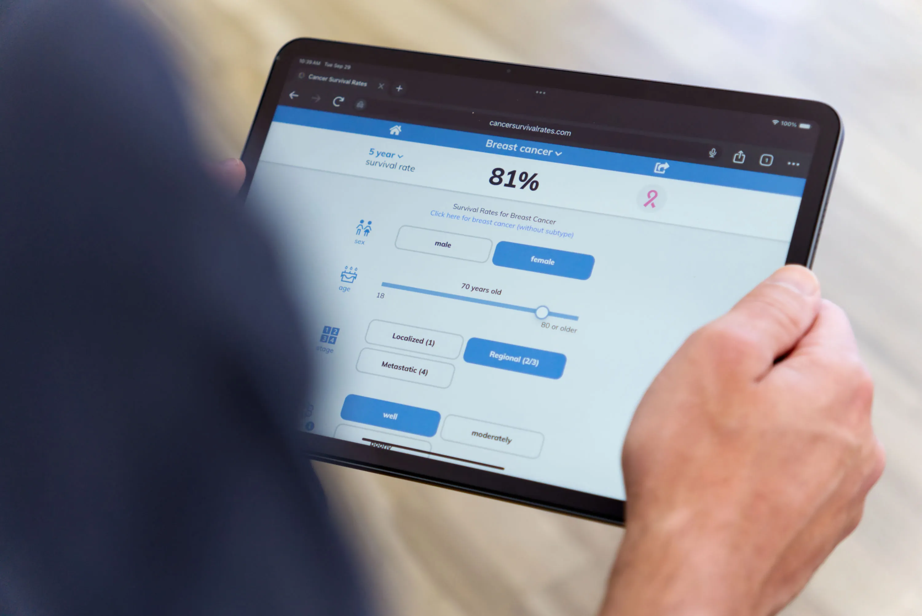 A person holding a tablet showing the CancerSurvivalRates.com home page.